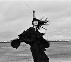 black and white photograph of woman in long dress with wind blowing her hair up to the side