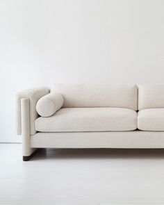 a white couch sitting on top of a hard wood floor next to a wall in an empty room