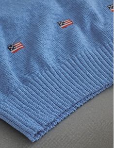 This sweater is a cozy and stylish piece, perfect for adding a touch of whimsy to your wardrobe. It is crafted from a soft, light blue knit fabric, ensuring both comfort and warmth. The design features a classic crew neck and long sleeves, making it suitable for cooler weather. A distinctive feature of this sweater is the pattern of small embroidered American flags scattered across the front, sleeves, and back. These flags are evenly spaced and add a playful, patriotic element to the garment. Th