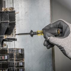 a person wearing gloves and holding a screwdriver in front of an electrical device