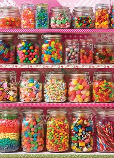 a shelf filled with lots of colorful candies and lollipops in glass jars