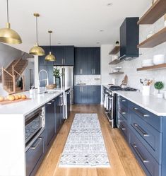 a kitchen with dark blue cabinets and white counter tops, gold pendant lights over the stove