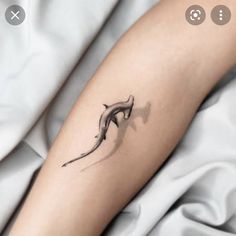 a woman's arm with a small tattoo of a dolphin on the left forearm