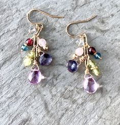 "Gemstone Dangle Earrings Cluster Earrings in Gold Fill Pink amethyst briolettes drop from shimmering gold fill, accompanied by a glorious cluster of tiny gemstones: Garnet, Iolite, Peridot, Rose Quartz, Fluorite, and London Blue Topaz. Lavishly wrapped in gold-filled wire, the genuine gemstones twinkle and sparkle fetchingly. Wire-wrapped to a paperclip link gold-filled chain, the earrings dangle from ball-tipped earring wires. Also available in lever back earring wires, which snap shut for gre Gemstone Accented Dangle Earrings, Multicolor Dangle Earrings With Gemstone Accents, Multicolor Gemstone Accented Drop Earrings, Multi-stone Dangle Earrings For Party, Multicolor Multi-stone Dangle Earrings, Dangle Crystal Earrings With Gemstone Accents As Gift, Dangle Multi-stone Earrings For Gifts, Teardrop Multi-stone Jewelry Making Supplies, Long Drop Multi-stone Earrings For Gift