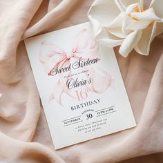 a pink and white birthday card with a large flower on top of it next to a blanket