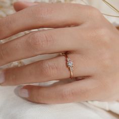 a woman's hand with a diamond ring on top of her finger and the other hand holding an engagement ring