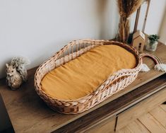 a wicker basket sitting on top of a wooden table next to a stuffed animal