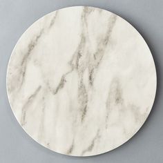 a round white marble coaster sitting on top of a gray surface with an abstract design