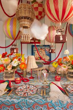 many colorful hot air balloons are in the sky above a table with flowers and other decorations