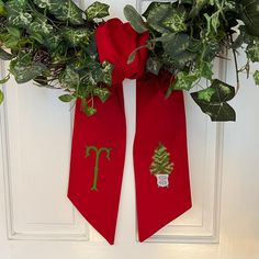 a christmas wreath is hung on the front door with two red ties hanging from it