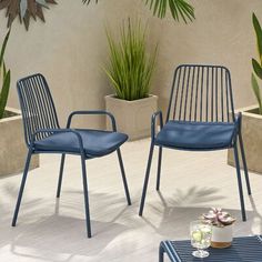 two blue chairs sitting next to each other on top of a white tile floor in front of a potted plant