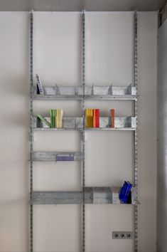 a metal shelf with books on it in a room next to a wall and door