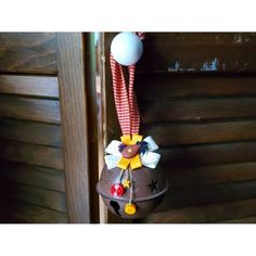 a christmas ornament hanging from the side of a wooden door with a red and white striped ribbon