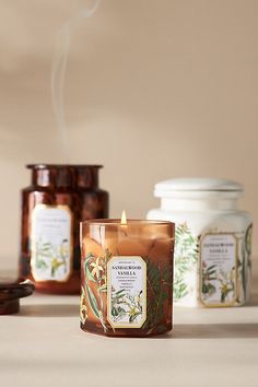 a candle sitting on top of a table next to two jars filled with tea leaves