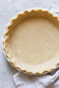 an uncooked pie crust sits on top of a white dish towel next to it