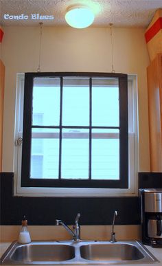 a kitchen sink under a window next to a coffee maker