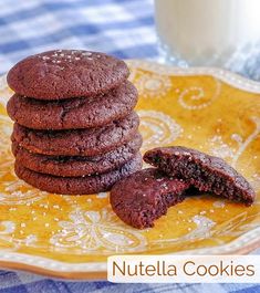 chocolate cookies are stacked on a plate with a glass of milk in the back ground