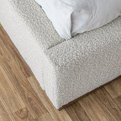 a white pillow sitting on top of a wooden floor next to a bed with two pillows