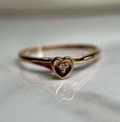 Tiny heart stackable gold ring with a small diamond set in the centre. Preloved item, previously resized, evidence of this can be seen Size (approx.): 7.75 US Stamped Dynasty 14K Weight: 1.436g **FREE shipping within Canada and USA** If you have any questions or concerns, please do not hesitate to contact us. We will be more than happy to help you and answer any inquiries.  We invite you to check out our shop for more fabulous items!v Classic Heart-shaped Stackable Promise Rings, Classic Stackable Yellow Gold Heart Ring, Diamond Heart Ring For Promise Occasions, Fine Jewelry Heart Shaped Single Diamond Ring, Diamond Heart Shaped Promise Ring, Heart Shaped Single Diamond Ring Fine Jewelry, Heart Shaped Single Diamond Fine Ring, Heart Shaped Single Diamond Ring, Stackable Rose Gold Heart Ring Fine Jewelry