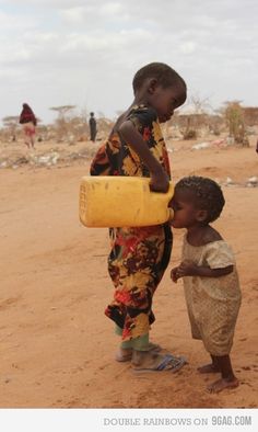 two young children standing in the dirt with a yellow container on their head and one holding a bottle