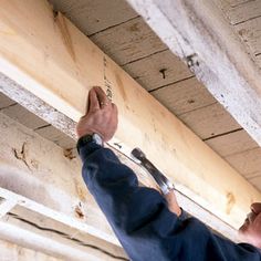 a man is working on the ceiling in an unfinished room with wood planks and nails