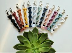 a bunch of crochet key chains sitting next to a succulent plant