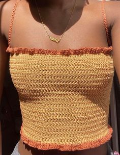 a close up of a woman wearing a yellow and orange crop top with an inscription on it