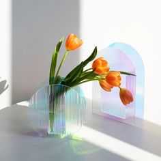 two vases with flowers in them sitting on a table