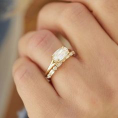 a woman's hand with a ring on it that has an oval shaped diamond in the middle