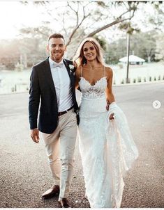 a bride and groom are walking down the street in their wedding attire, holding hands