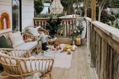 two children are playing on the front porch with wicker furniture and rugs around them