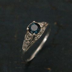 a ring with a blue stone in the center on a black surface and gold accents