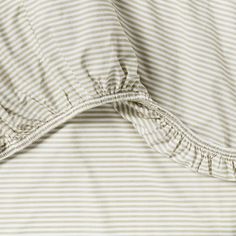 an unmade bed with white and grey striped sheets on it's side, close up