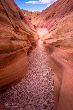 a narrow river in the middle of a canyon with rocks on both sides and blue sky above