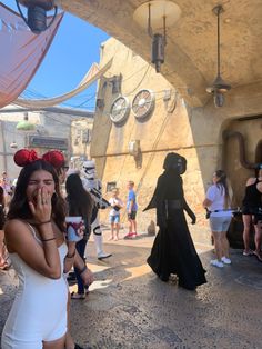 a woman in a white dress is talking on her cell phone while others are dressed as darth vader