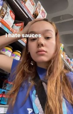 a girl with long hair standing in front of a store shelf and looking at the camera