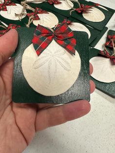 a hand holding a christmas ornament with red and black bows