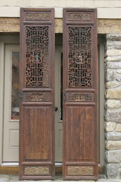 two wooden doors are open on the outside of a building with stone walls and windows