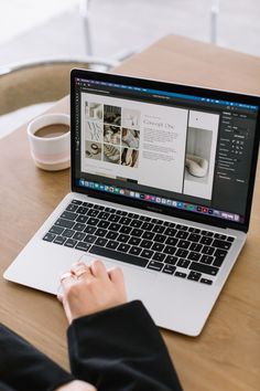 a person sitting at a table with a laptop on their lap and coffee in front of them