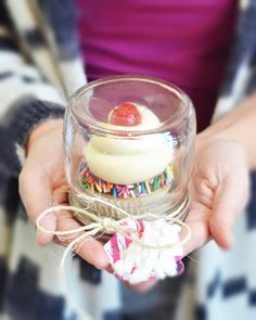 a person holding a small glass container filled with cake and marshmallows in their hands