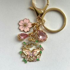 a keychain with several charms attached to it on a white surface and a pink flower in the center