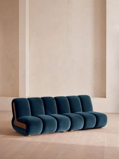 a blue couch sitting on top of a hard wood floor next to a white wall