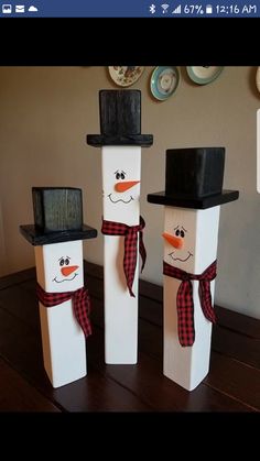 three snowmen with hats and scarfs are standing in front of each other on a table