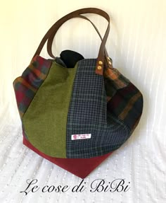 a multicolored handbag sitting on top of a white bed next to a wall