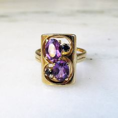 This is a vintage 14K yellow gold ring set with large 5mm x 7mm oval amethyst gemstones.  The two amethysts have a total carat weight of 1.50 carats.  There are 2 round 2.1mm sapphires with a total carat weight of .06ct.  The ring face measures 5/8" long x 7/16" wide.  The band is sized at 6 3/4.  Total weight of the ring is 6.5grams/4.2dwt. This is a vintage, previously owned ring.  Therefore, light wear can be expected.  There is no visible damage. The Ring Face, Amethyst Gem, Gold Ring Sets, Purple Band, Gifts For My Sister, Yellow Gold Ring, Amethyst Gemstone, Yellow Gold Rings, Rings Statement