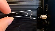 a hand is holding a metal object in front of a black box with wires attached to it