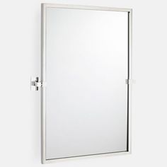 a mirror mounted to the side of a wall next to a white cabinet and door