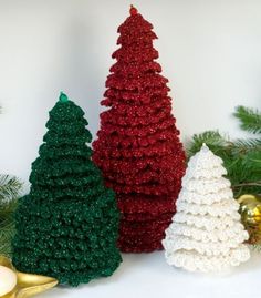 three crocheted christmas trees sitting next to each other