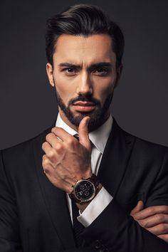 a man in a suit and tie with his hand on his chin looking at the camera