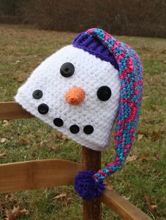 a crocheted snowman hat on top of a wooden fence